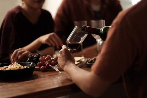 Friends sharing red wine at a table — wines like Meiomi, from Cambridge Wines